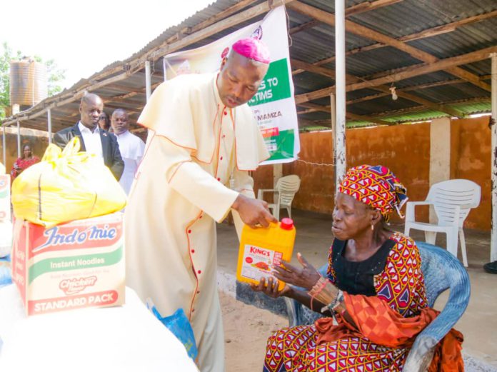 Mamza distributing the items to a victim of the clash.